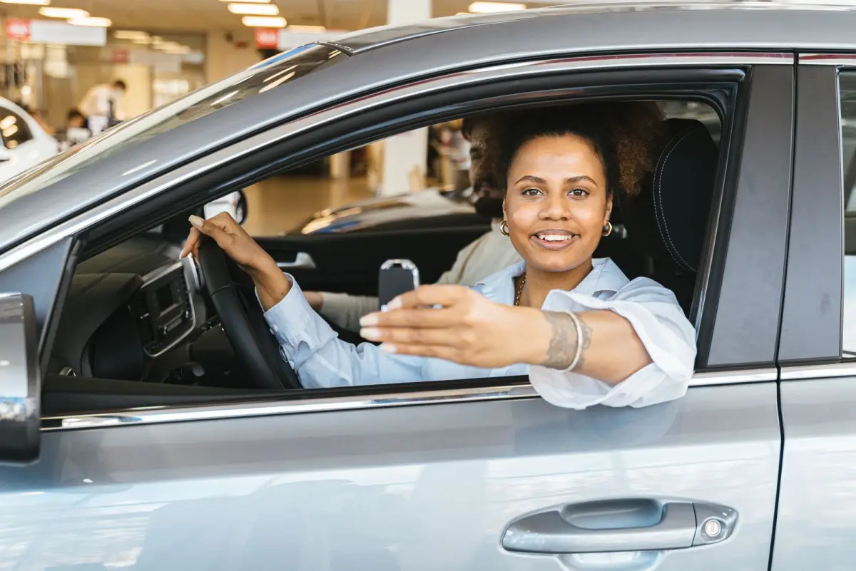 A driver in her new car, smiling and holding the keys